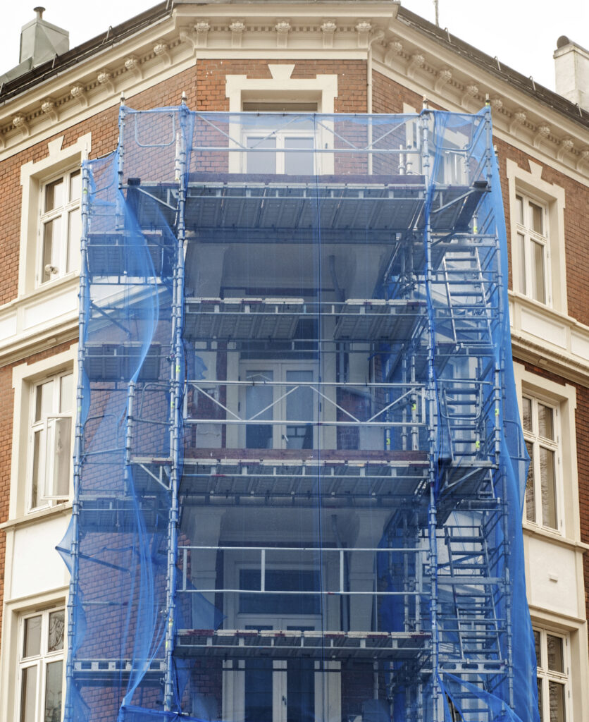 Immeuble ancien en cours de rénovation avec échafaudages et dispositifs de protection en façade.