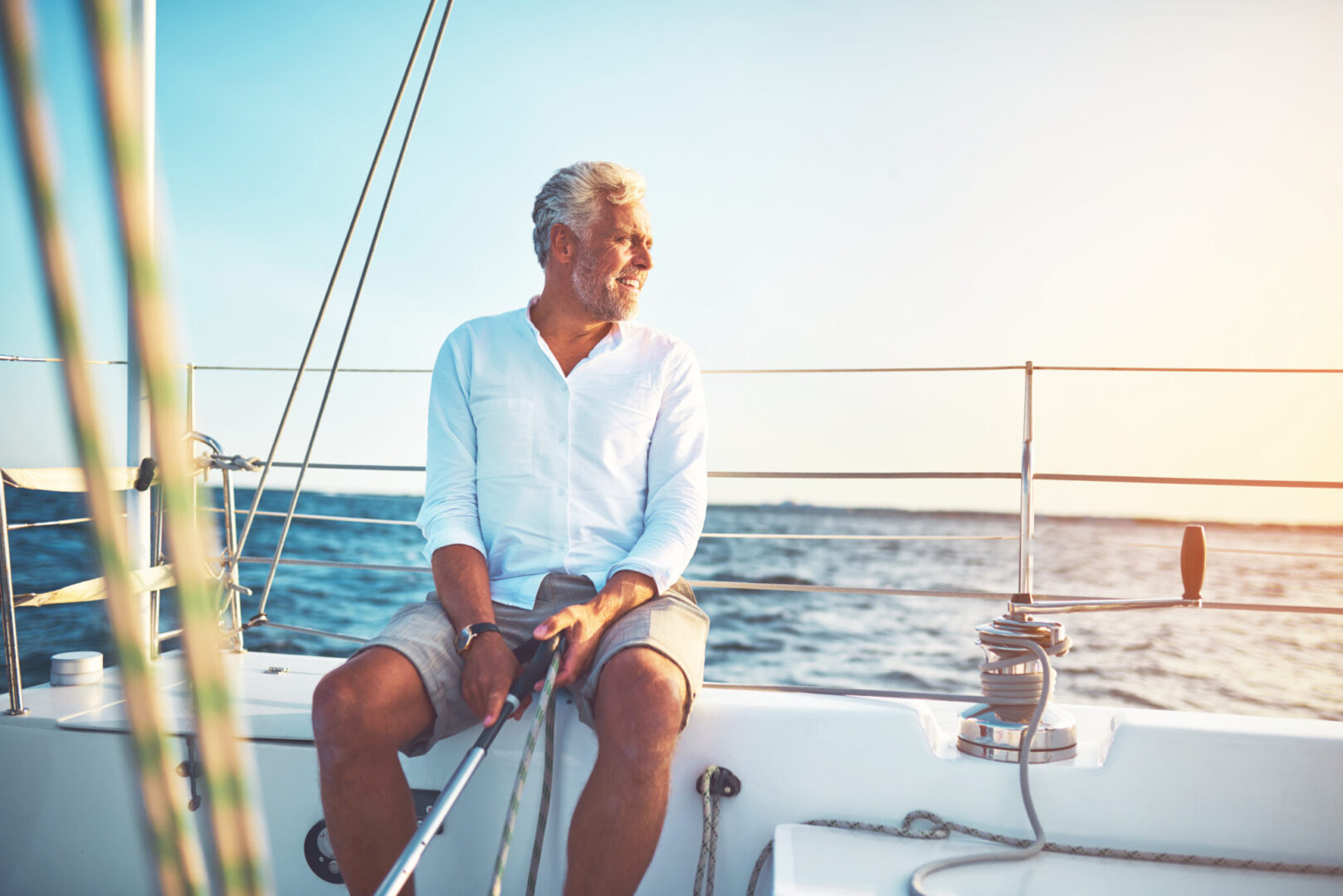 Personne assise à bord d’un voilier, tenant une écoute en pleine navigation.