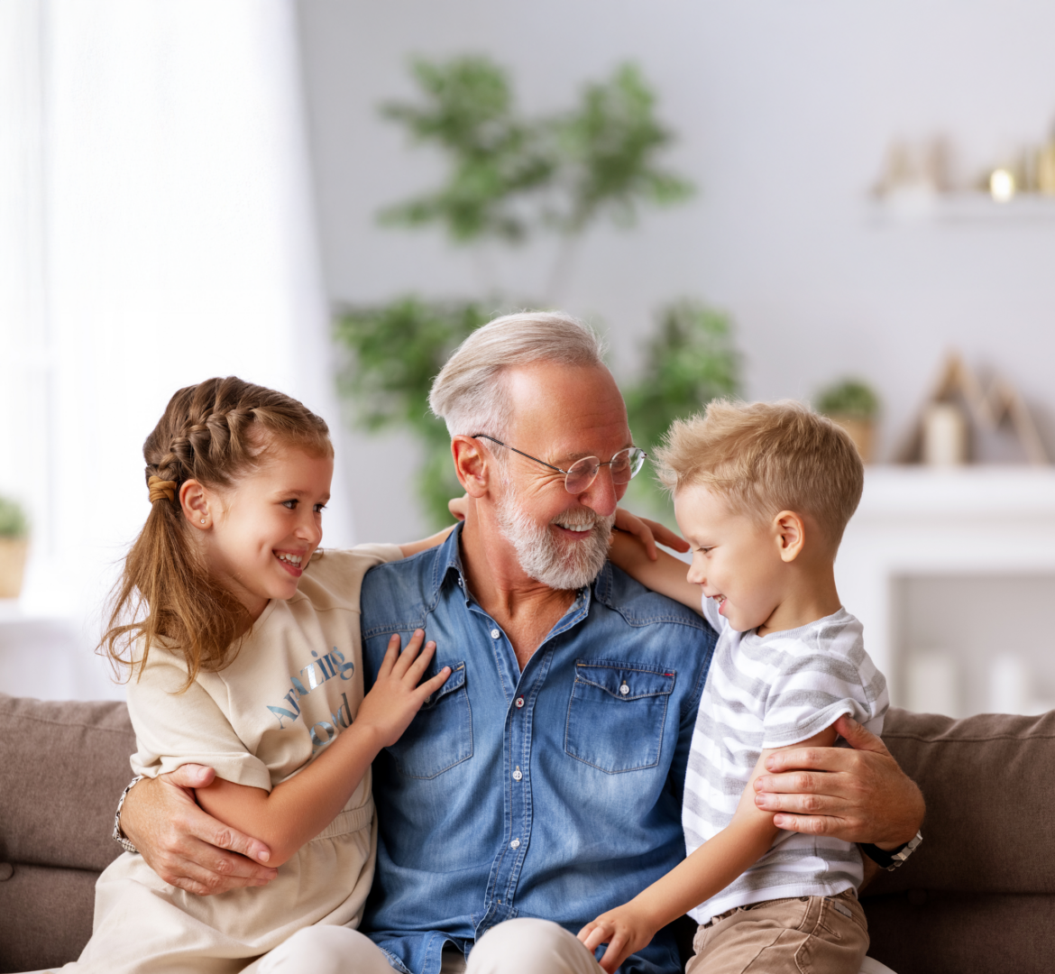 Personne âgée assise sur un canapé avec deux enfants dans un intérieur lumineux.