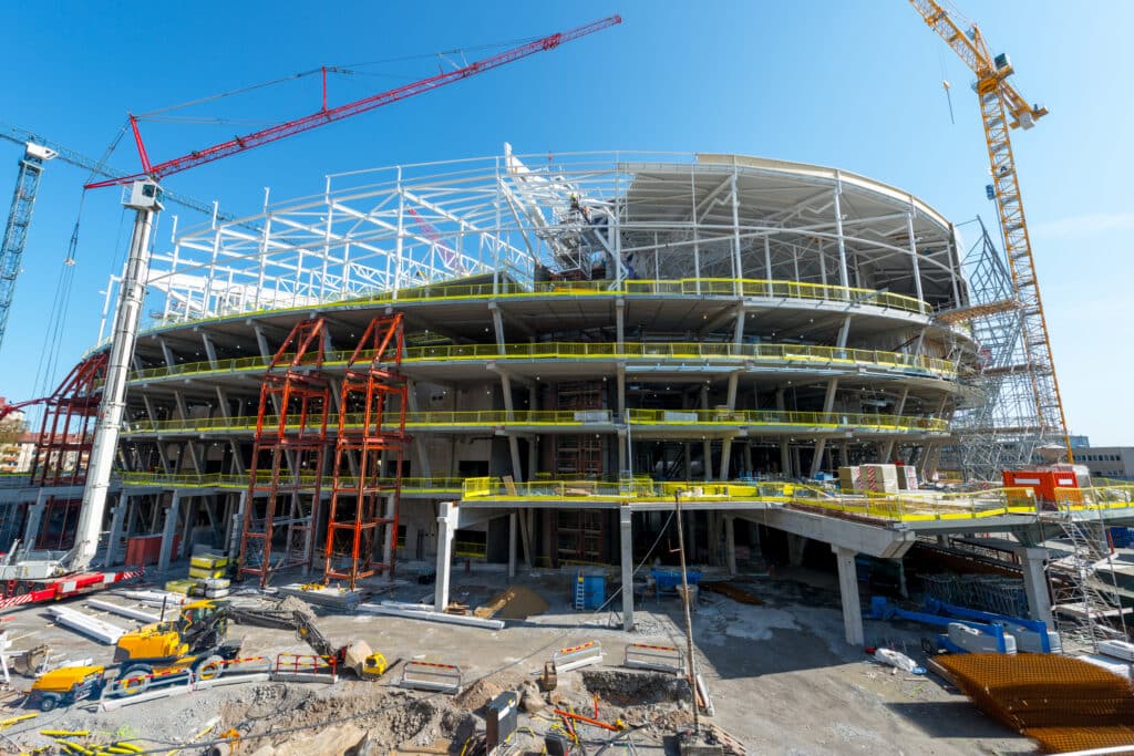 Chantier de construction d’un bâtiment de grande dimension avec structures métalliques et grues en activité