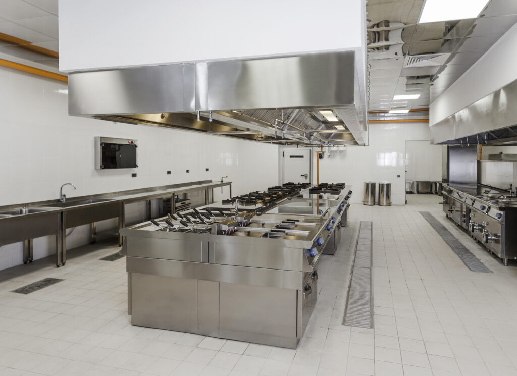 Cuisine professionnelle entièrement équipée avec plans de travail en inox, appareils de cuisson et systèmes d’extraction.