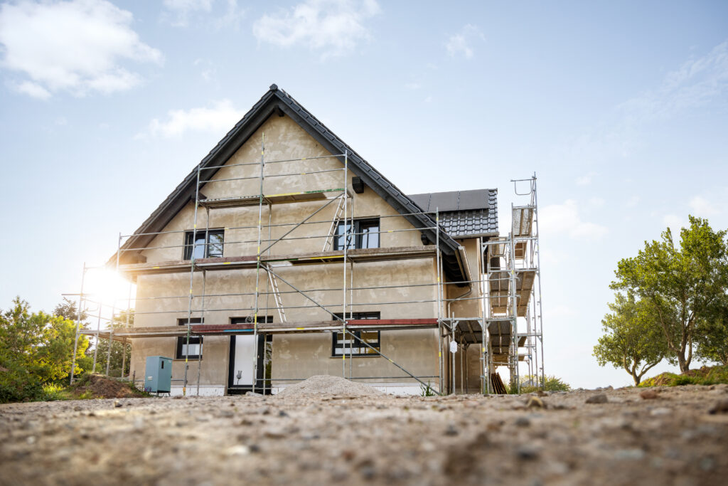 Maison individuelle en cours de rénovation avec échafaudages et travaux sur la structure extérieure.