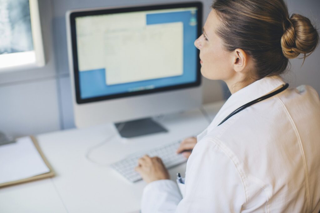 Professionnel de santé utilisant un poste informatique pour consulter et gérer des informations médicales.