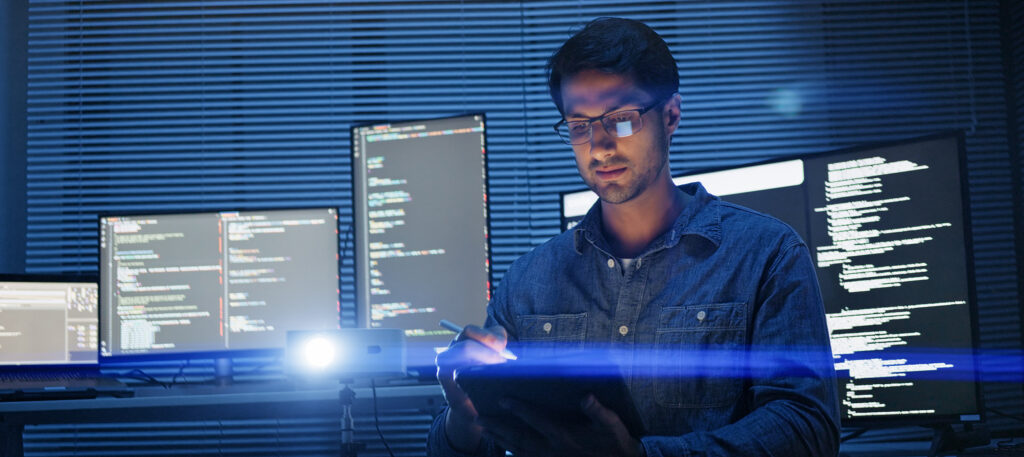 Poste de travail sécurisé avec écrans affichant des lignes de code, illustrant la surveillance et la protection des systèmes informatiques.