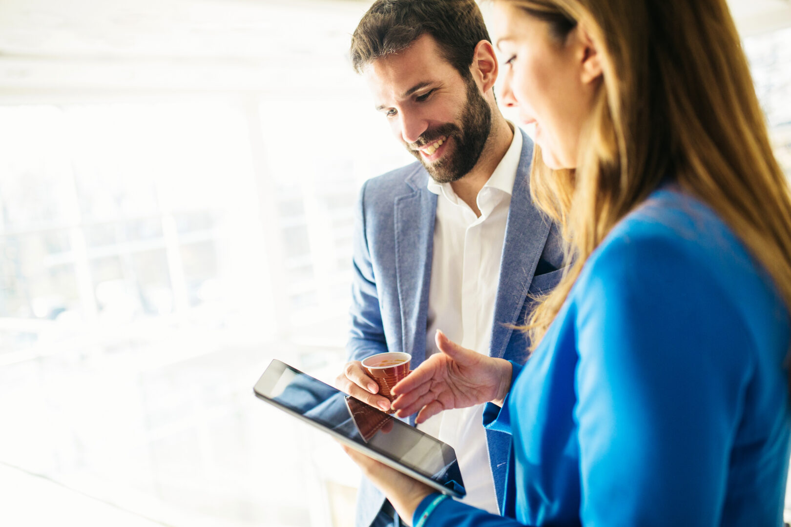 Échange professionnel entre deux personnes autour d’une tablette numérique pour analyser des solutions financières.