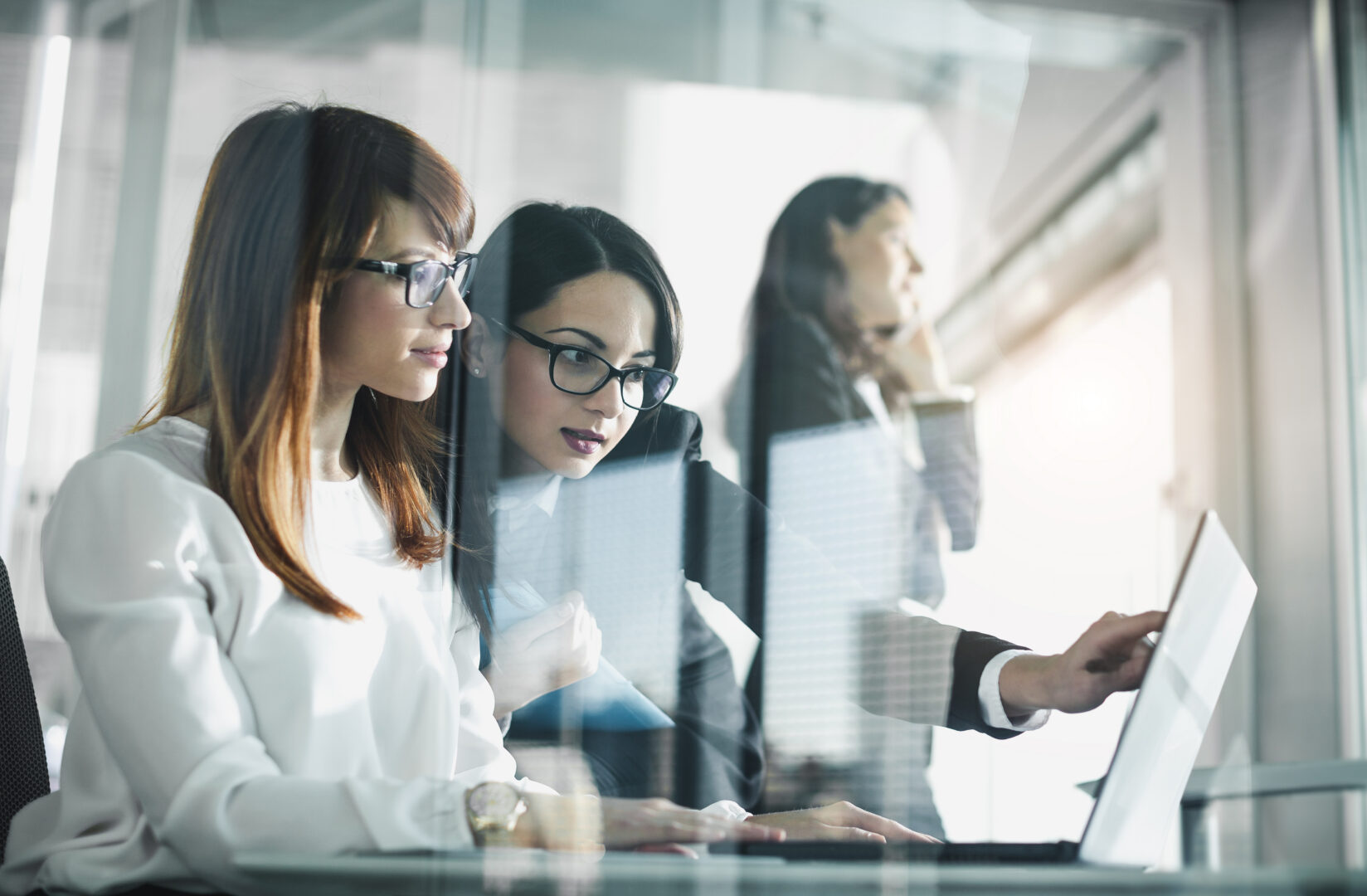 Équipe professionnelle utilisant des outils numériques collaboratifs dans un environnement de travail moderne.