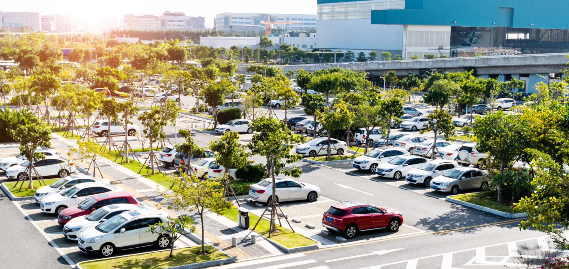 Parking d’entreprise avec de nombreux véhicules stationnés dans un environnement urbain végétalisé