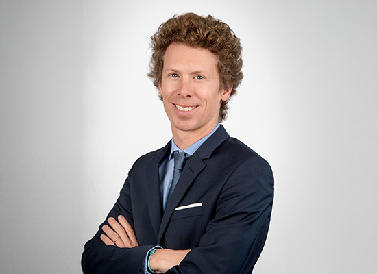 Portrait professionnel d’une personne en costume sur fond neutre.