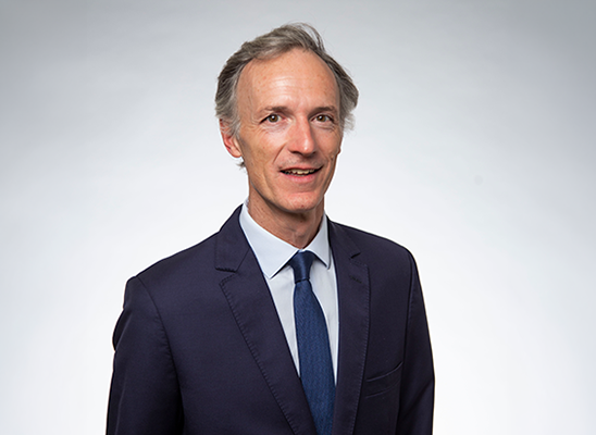 Portrait professionnel d’une personne en costume sur fond neutre.